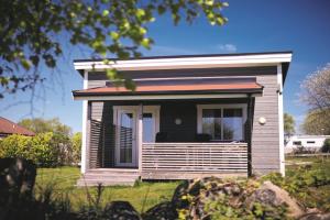 una piccola casa con un grande portico su un prato di Hälleviks Camping a Sölvesborg