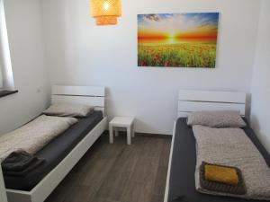 two beds in a room with a painting on the wall at PARSBERGER STADTWOHNUNG 3 in Parsberg