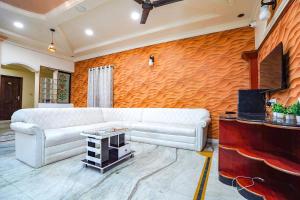 ein Wohnzimmer mit einem weißen Sofa und einer orangefarbenen Wand in der Unterkunft FabHotel The Imperial Green in Nagpur