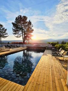 une piscine avec une terrasse en bois et un coucher de soleil dans l'établissement Domaine du Val de Sault, à Sault