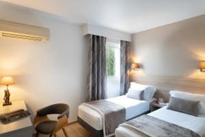 una camera d'albergo con due letti e una sedia di Golfe Hotel a Porto Vecchio