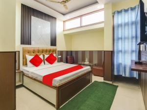OYO Hotel HHH في شانديغار: غرفة نوم بسرير كبير ومخدات حمراء