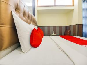OYO Hotel HHH في شانديغار: غرفة نوم بسرير ومخدة حمراء