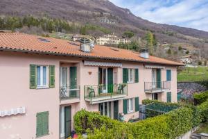 a building with green doors and windows and a mountain at Bonardi's Home - enjoy the lakes! in Carlazzo