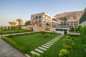 a building with a lawn and a building with mountains in the background at Al Masa Hotel El Sokhna in Ain Sokhna