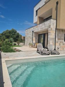 una casa con 2 sillas y una piscina en Villa Leonardo, en Tribunj