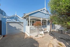 a blue house with a gate and a garage at Swyn Y Mor Riverside Cottage Haven in Ocean Grove