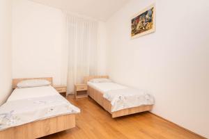 two beds in a room with white walls and wooden floors at Apartment Hani Koper in Koper