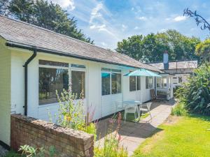 a white cottage with a patio and an umbrella at Beach View Cottage in Felixstowe