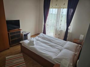 1 dormitorio con 1 cama blanca y TV en Pensiunea Printul Vlad, en Sibiel