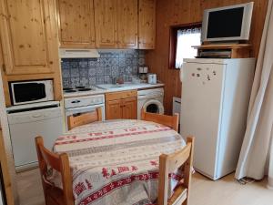a kitchen with a table and a white refrigerator at Studio Cabine, plein centre de Valloire in Valloire