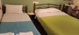 two beds with colorful sheets in a room at Hotel zakros rooms-restaurant in Zákros