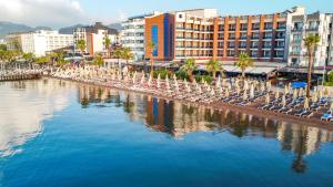 a beach with chairs and palm trees and buildings at point beach hotel in Marmaris