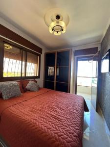 una camera da letto con un letto grande con un piumone rosso di Charmant appartement bien situé. a Martil