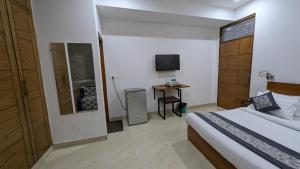 1 dormitorio con 1 cama y escritorio con TV en Hotel Prime Chhatarpur, en Nueva Delhi