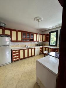 a large kitchen with white appliances and brown cabinets at Huzur dolu bi villada konaklama in Çarşıbaşı