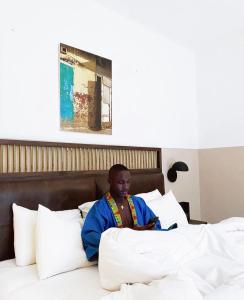 a man sitting on top of a bed at Hotel Lepic in Abidjan