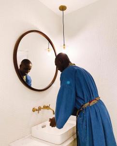 Una donna in piedi in un lavandino davanti a uno specchio di Hotel Lepic a Abidjan
