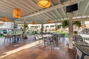 een patio met tafels en stoelen en een flatscreen-tv bij Apartamentos LIVVO Koala Garden in Maspalomas