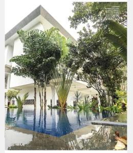 a building with a pool with trees in front of it at Hotel Lepic in Abidjan