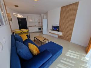a living room with a blue couch and a kitchen at Апартамент МеГи in Burgas
