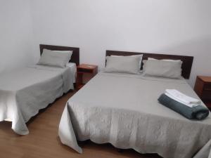 two beds in a bedroom with a suitcase on it at Mônaco Hotel in Juiz de Fora