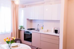 a kitchen with white cabinets and a table with flowers at Central White Apartment in Satu Mare