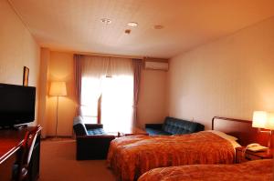 a hotel room with two beds and a television at Yatsugatake Grace Hotel in Minamimaki