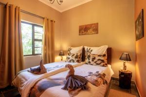 two birds sitting on a bed in a bedroom at Ijaba Lodge at Buschfeld Park in Outjo