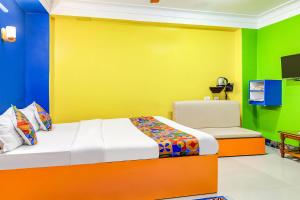 een slaapkamer met kleurrijke muren en een bed en een stoel bij FabHotel Relax in Bāghdogra