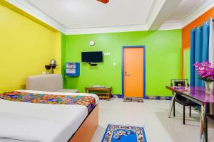 1 dormitorio con paredes coloridas, 1 cama y escritorio en FabHotel Relax en Bāghdogra