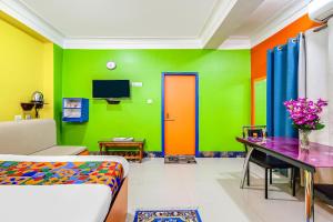 uma sala de estar com uma parede verde e laranja em FabHotel Relax em Bāghdogra