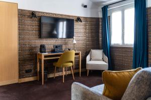 um quarto com uma secretária e uma televisão na parede em Hôtel Artus em Paris