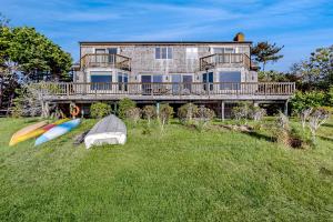 ein Haus mit zwei Surfbrettern auf dem Gras davor in der Unterkunft Cape Springs Cottage in Chatham