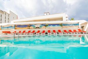 a swimming pool with red chairs and a building at point beach hotel in Marmaris