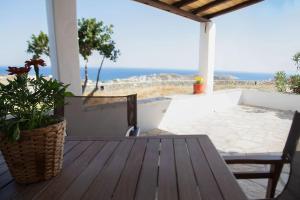 a porch with a wooden table and a view of the ocean at Amarados Studio Syros in Vari