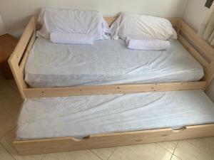 una cama de madera con sábanas blancas y almohadas. en Oliva Mar, en Lloret de Mar