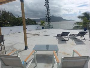 a table and chairs on a patio with a view of the water at Appartement moderne face à la mer in Mahébourg