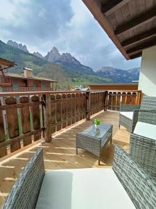 a deck with chairs and a table with a view of mountains at Casa Paola in Pozza di Fassa