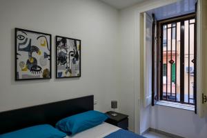 a bedroom with a bed with blue pillows and a window at Casa Vacanze Nemesi AURA in Salerno