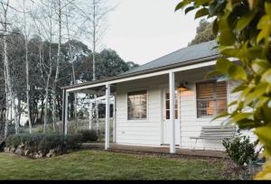 a white cottage with a porch and a bench at Peony Farm Pink Cottage in Stanley