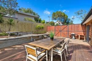 托基Sunset Sanctuary 500m to beach Pet Friendly的露台上的木桌和椅子