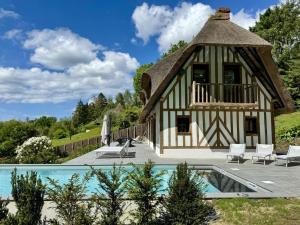 a house with a thatched roof and a swimming pool at Villa Pier'Art - Piscine Jacuzzi Tennis Vue Mer in Touques