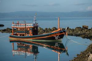 a boat sitting in the water with its reflection at Neptune's Villa in Haad Rin