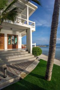 a white house with a palm tree next to the ocean at Neptune's Villa in Haad Rin