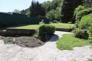 a garden with a retaining wall and some plants at Ferienhaus mit Schwimmbad, Whirlpool & Sauna am Nürburgring in Leimbach