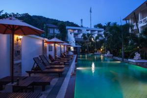 a swimming pool with chairs and umbrellas at night at Neptune's Villa in Haad Rin