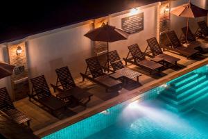 a group of chairs with umbrellas next to a swimming pool at Neptune's Villa in Haad Rin