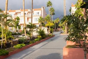 a walkway in front of a building with palm trees at Hotel El Duque in Adeje