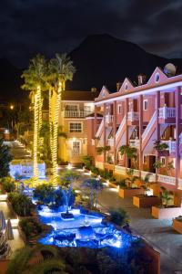 un complexe avec une piscine et des palmiers la nuit dans l'établissement Hotel El Duque, à Adeje